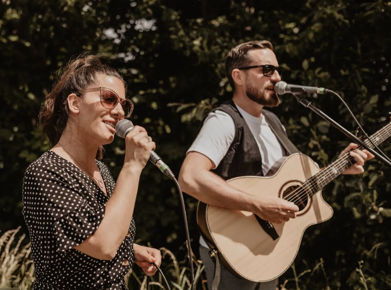 Jenny singt, Manuel spielt akustische Gitarre – draußen im Grünen